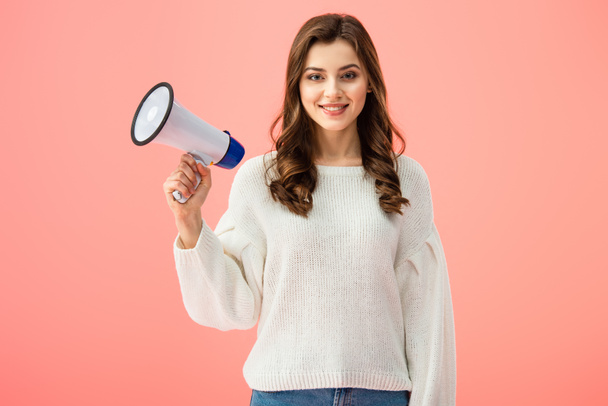 smiling woman in white sweater holding megaphone isolated on pink - Foto, immagini