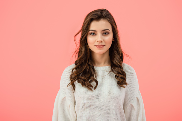 smiling and attractive woman in white sweater looking at camera isolated on pink - Photo, Image