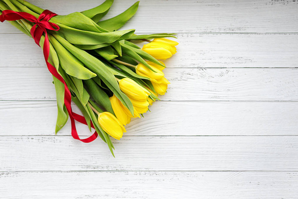 Bukiet żółtych tulipanów kwiaty na białym tle drewnianych. Czekam na wiosnę. Szczęśliwa karta Wielkanoc, dzień matki, 8 marca. Płaskie położenie, widok z góry. - Zdjęcie, obraz