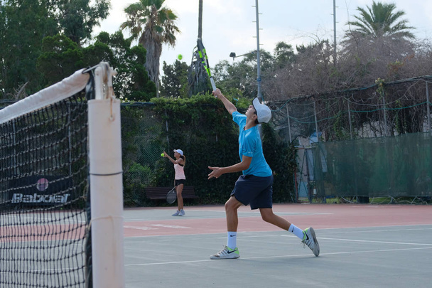 Izrael - Netanya, 27 července 2018: mladý muž v košili sportovní a sportovní šortky hraje na tenisový kurt v tenise - Fotografie, Obrázek