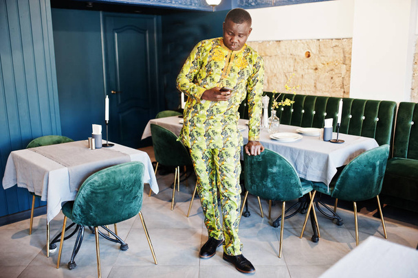 Friendly afro man in traditional yellow clothes at restaurant, m - Φωτογραφία, εικόνα