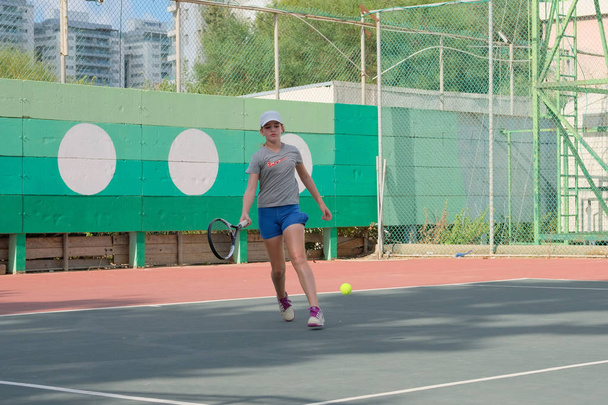 ISRAEL - Нетания, 27 июля 2018 года: молодая девушка играет в теннис в спортивной рубашке в спортивных шортах бегает по площадке бьет мяч выполняет подачу на турнире в Израиле
 - Фото, изображение