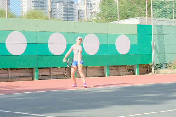 Νετάνια, Ισραήλ - 27 Ιουλίου 2018: ένα νεαρό κορίτσι παίζει τένις σε ένα πουκάμισο σπορ αθλητικά σορτς τρέχει γύρω από το δικαστήριο χτυπά η σφαίρα εκτελεί την κατάθεση στο τουρνουά στο Ισραήλ - Φωτογραφία, εικόνα