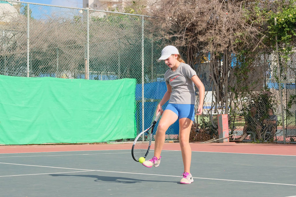 Israël - Netanya, 27 juli 2018: een jong meisje speelt tennis in een sport shirt in sport korte broek loopt rond de Hof-beats de bal voert de indiening bij het toernooi in Israël - Foto, afbeelding