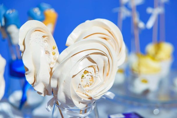 Λευκή μαρέγκα με τη μορφή τριαντάφυλλων. Γλυκό επιδόρπιο. Σοκολάτα. Μαρέγκα σε ξύλινα ραβδιά. Προϊόν ζαχαροπλαστικής. - Φωτογραφία, εικόνα