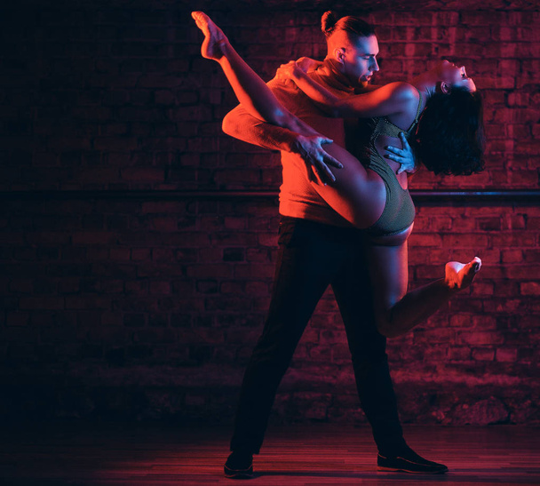 Красива пара танцює на танцмайданчику в нічному клубі. Танцюристи виступають в темряві з підсвічуванням
 - Фото, зображення