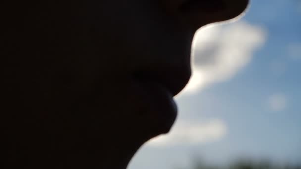 Vrouwelijk gezicht silhouet eten wat voedsel uit een lepel buitenshuis in slow motion - Video