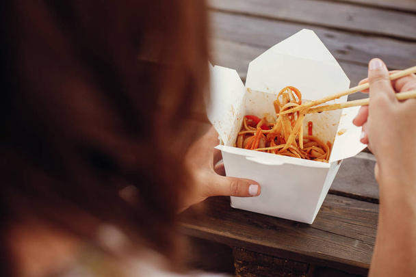 Girl eating wok noodles with vegetables and seafood in carton bo - Foto, immagini