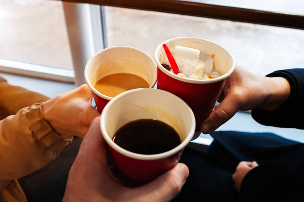 cerrar las manos con tazas de café a la hora de los vítores. amigos se divierten y beben café en la cafetería
 - Foto, Imagen