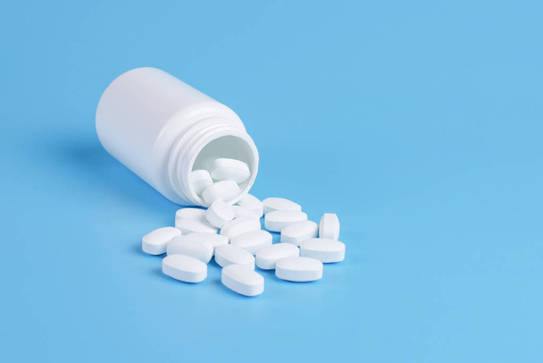 Geneeskunde witte pillen of tabletten drop uit de witte fles op  - Foto, afbeelding