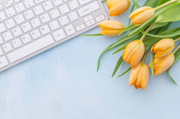 Tastiera del computer portatile e tulipani gialli su sfondo azzurro. Primavera estate decorato fiore, desktop, piatto lay top vista copia spazio
 - Foto, immagini