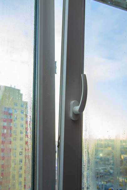 Řešení problému - mlžení plastových oken - větrání. Za oknem rozmazaný obraz domů - Fotografie, Obrázek