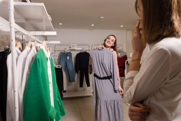 Usmívající se žena vyzkoušet na dlouhé šaty v obchodě s šaty. - Fotografie, Obrázek