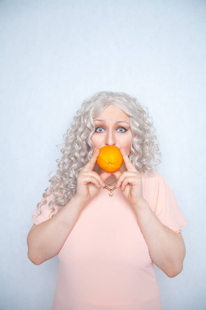charming plump curly blonde in pink dress with orange on white solid studio background alone - Photo, image