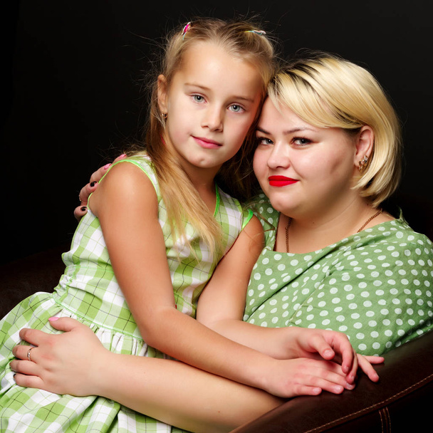 Mom and daughter are hugging on a black background. - Foto, imagen