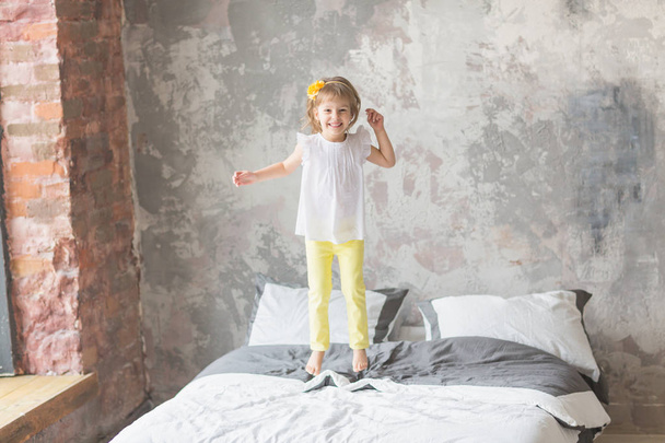 Happy child girl having fun jumping on a bed - Photo, image