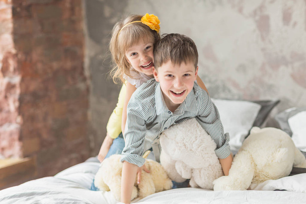 Brother and sister playing with teddy bear in bed - Fotografie, Obrázek