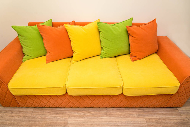 un colorato divano giallo-arancio con cuscini verdi, gialli e arancioni
 - Foto, immagini