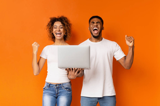 Excited black couple celebrating win with laptop - 写真・画像