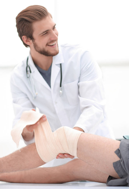 doctor looking at the bandage on the patients leg - Foto, afbeelding