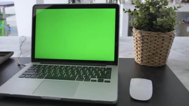 Laptop computer met groen Chroma-toetsen scherm staat op een bureau in de woonkamer. In de achtergrond gezellige woonkamer. Dolly schot van rechts naar links. 4k - Video