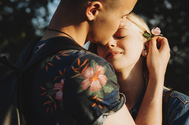 Beautiful european couple embracing while man is putting a flowe - Photo, Image