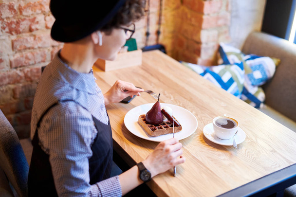 Giovane donna contemporanea seduta al tavolo nel caffè e prendere il tè con dessert alla pera dopo pranzo
 - Foto, immagini