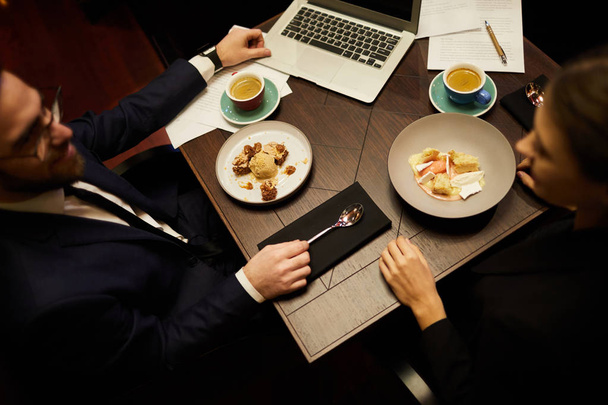 Δύο συνεργάτες που κάθονται από τραπέζι σε εστιατόριο, πίνοντας καφέ με γλυκό και διαπραγμάτευση ή προετοιμασία παρουσίαση ή νέο έργο - Φωτογραφία, εικόνα