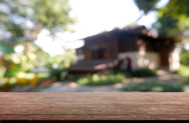 Puste drewniane tabela przed streszczenie dom niewyraźne i zielony ogród. - Zdjęcie, obraz