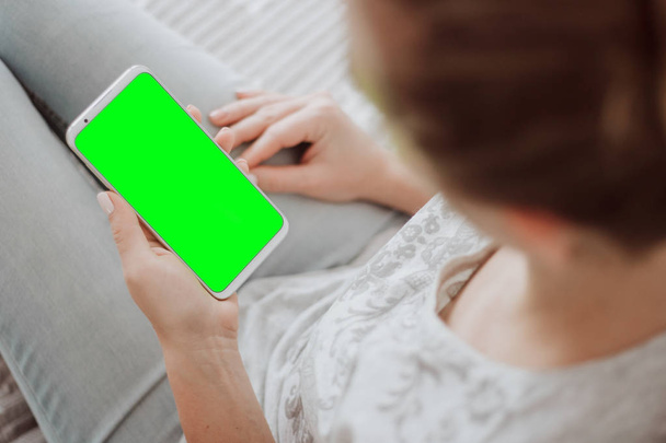 Chroma-Schlüssel. Nahaufnahme. Green Screen Smartphone. Frauenhände mit Handy-Attrappe. - Foto, Bild