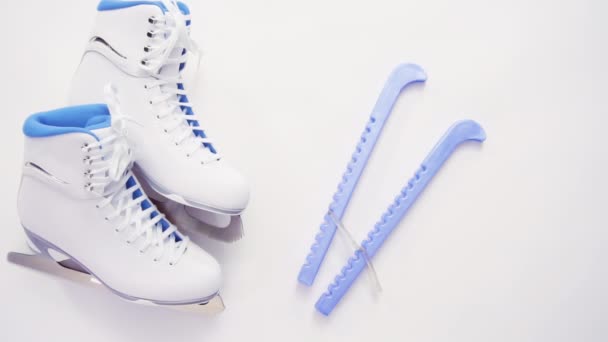 Acostado. Nueva figura blanca patina con protectores de patines azules sobre fondo blanco
. - Imágenes, Vídeo
