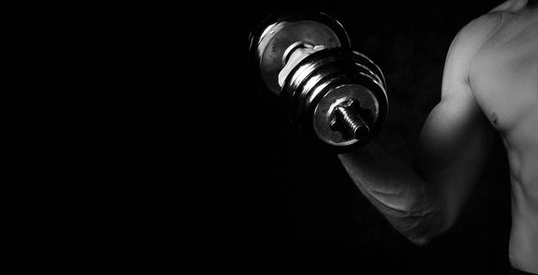Part of man's body with metal dumbbell on a dark background - Foto, Imagem
