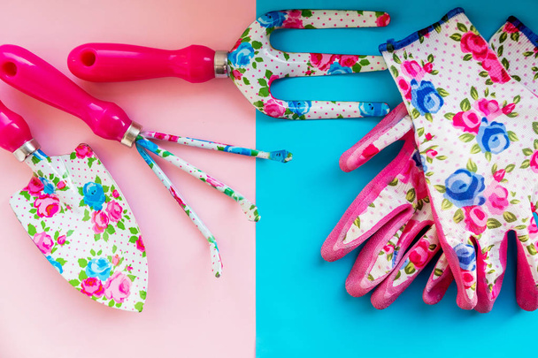 Metal garden tools and Rubber safety gloves on pastel pink blue background.working in garden. Hand shovel and gardening rake with gloves. Agriculture and gardening concept.Spade fork and rake.Spring - 写真・画像