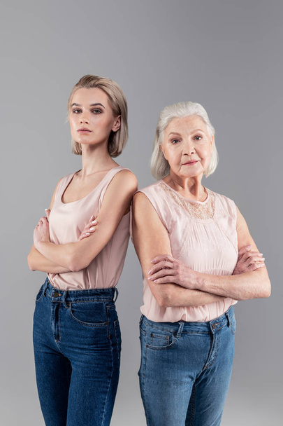 Grave same-looking ladies wearing blue jeans and light tops - Фото, изображение