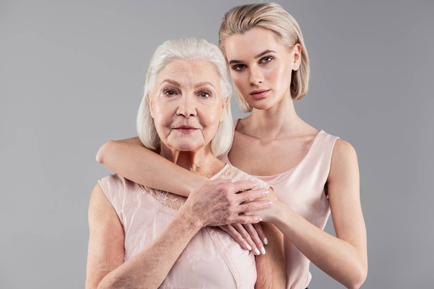 Pleasant old lady and her appealing blonde girl showing their relationships - Foto, Bild