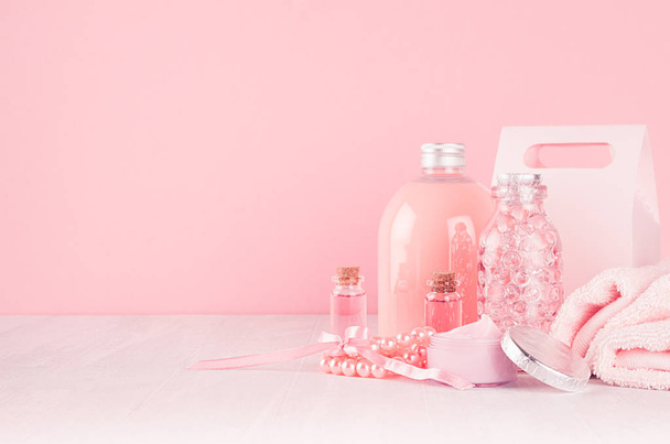 Cosmetics products for bath, spa - essential oil, bath salt, cream, liquid soap, towel in delicate pastel pink  bathroom interior. - Фото, изображение