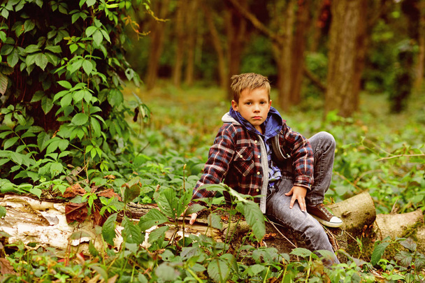 A halt in the woods. Small boy halt and relax sitting on tree in forest. Small boy resting on nature. You cant halt time - Foto, immagini
