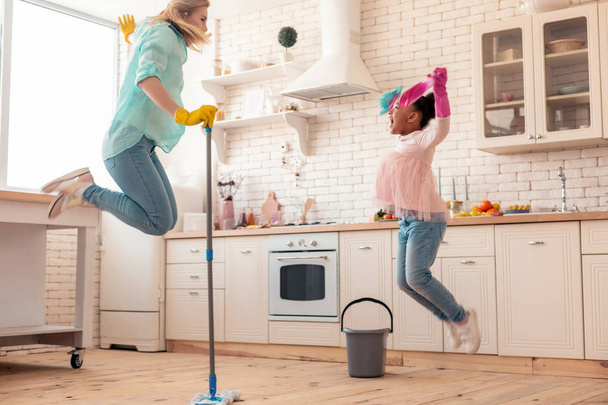 Matka i córka skoków podczas mycia podłogi - Zdjęcie, obraz