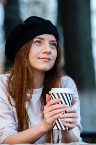 Beautiful woman holding paper coffee cup in the cityYoung stylish woman drinking coffee to go in a city street  - Fotó, kép