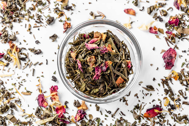 Green tea with dried flower petals and pieces of citrus in a glass bowl. Dried tea for welding. Diet and healthy drink. Flatley. Top view - Foto, Bild