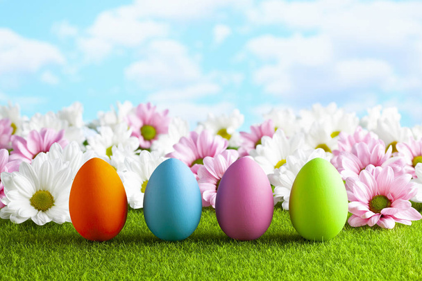 Easter eggs and flowers on the grass and blue sky background - Fotó, kép