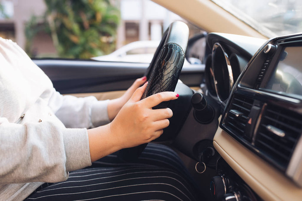 asiatische weibliche Hände am Lenkrad eines Autos während der Fahrt mit Windschutzscheibe und Straße. Schwarze Frauenhände halten selbstbewusst ein Lenkrad. Hände am Steuer - Autofahrerin - asien - Foto, Bild