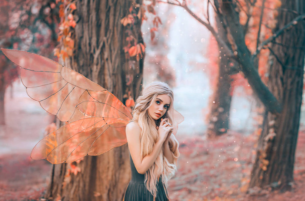 bright summer photo with shining rays of sun, mysterious forest fairy fell in love with prince, girl with puppet face, blond long hair and blue eyes, lady in green dress peeps modestly, with interest - Fotografie, Obrázek