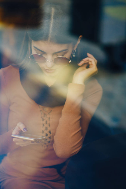 brunette girl using phone while at a restaurant - Фото, зображення