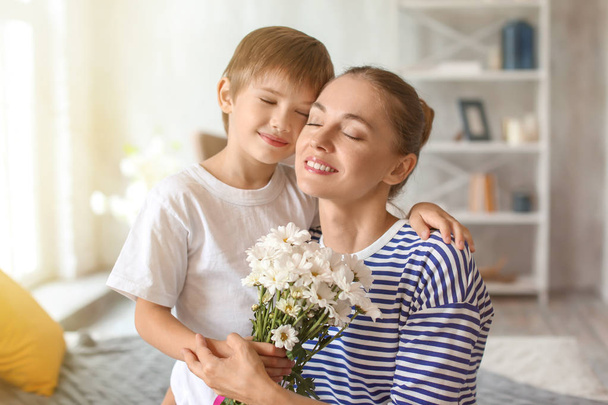 Η μητέρα λαμβάνουν τα λουλούδια από το χαριτωμένο μικρό γιο της στο σπίτι - Φωτογραφία, εικόνα