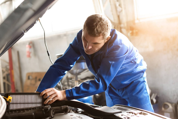 Mannelijke mechanic onderzoeken auto in servicecentrum - Foto, afbeelding