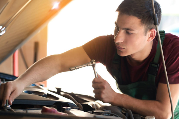 Jonge auto monteur reparatie auto in servicecentrum - Foto, afbeelding