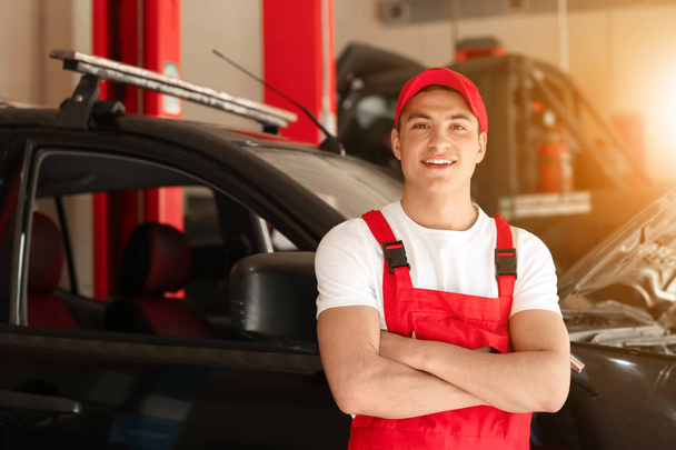Young auto mechanic near car in service center - Photo, Image