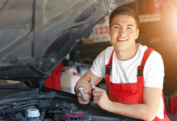 junger Automechaniker repariert Auto im Service-Center - Foto, Bild