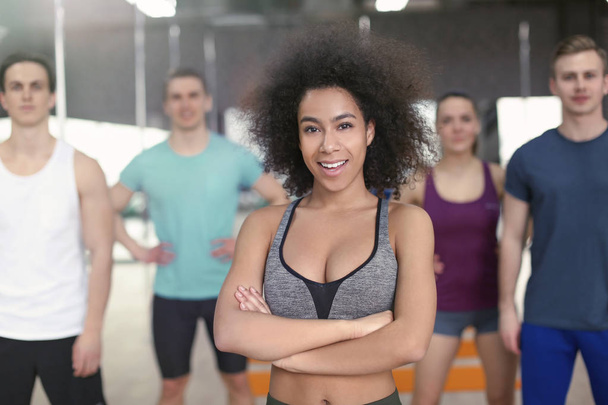 Sporty African-American woman with group of athletes in gym - Foto, Imagem